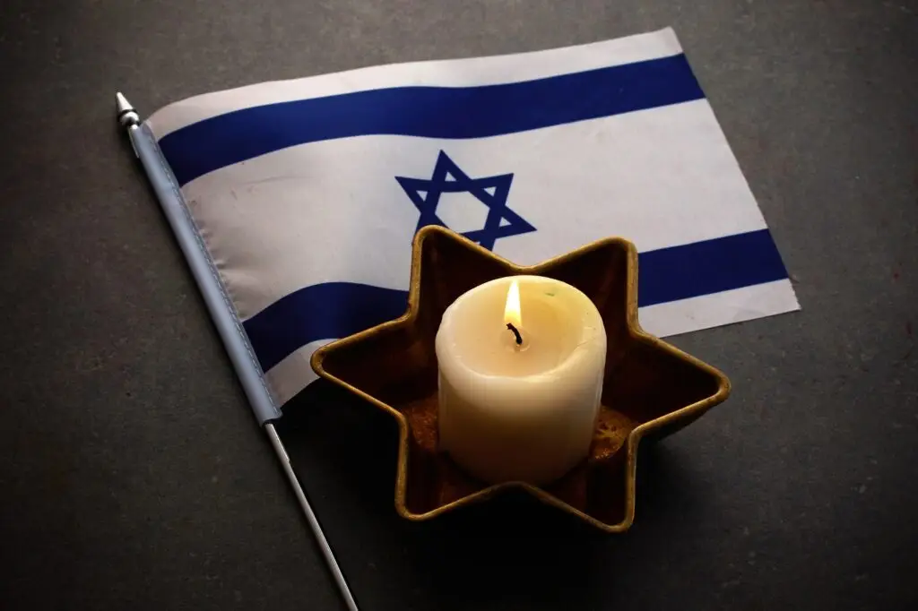 Burning candles and flag of Israel on dark background. Holocaust remembrance day