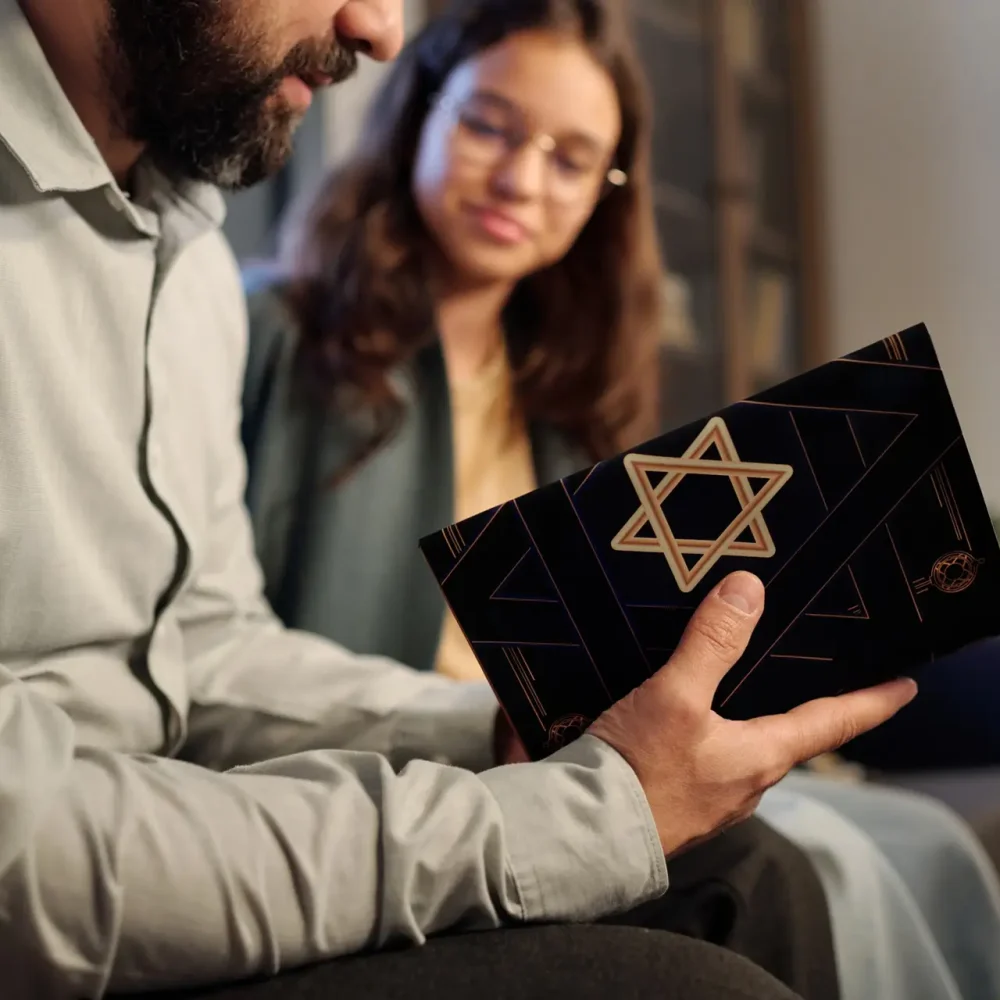 Focus on black cover of Torah with star of David in hands of bearded rabbi